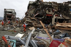 Firefighters inspect the damage on a building ruined by Friday's earthquake and tsunami in Minamisanriku, Miyagi Prefecture, Japan, Tuesday, March 15, 2011. (AP Photo/Shuji Kajiyama)