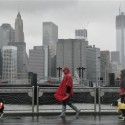 Peter Cusack, center, and Mel Bermudez walk their dogs Teague, left, and Molly along the Brooklyn waterfront beneath the New York skyline as Hurricane Sandy advances on the city, Monday, Oct. 29, 2012. Hurricane Sandy continued on its path Monday, forcing the shutdown of mass transit, schools and financial markets, sending coastal residents fleeing, and threatening a dangerous mix of high winds and soaking rain.  (AP Photo/Mark Lennihan)